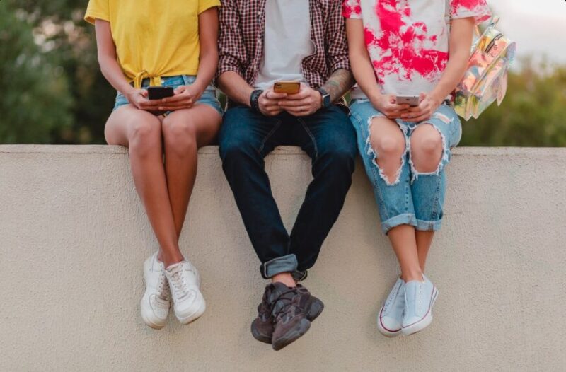Children sitting and looking to their smartphones