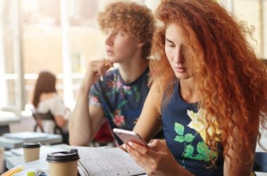 A student in a classroom looking at a smartphone