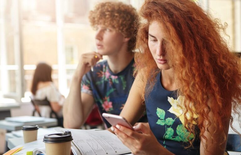 A student in a classroom looking at a smartphone