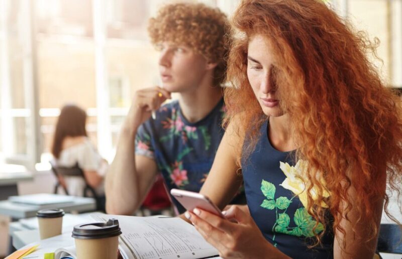 A student in a classroom looking at a smartphone