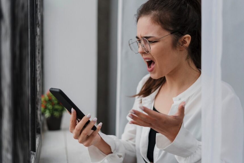 Young woman getting angry while looking at her smartphone