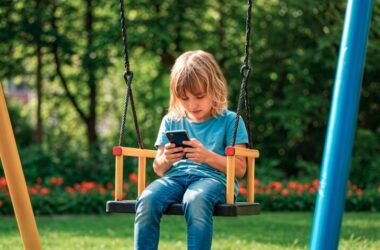 A young girl on a swing looking at a smartphone