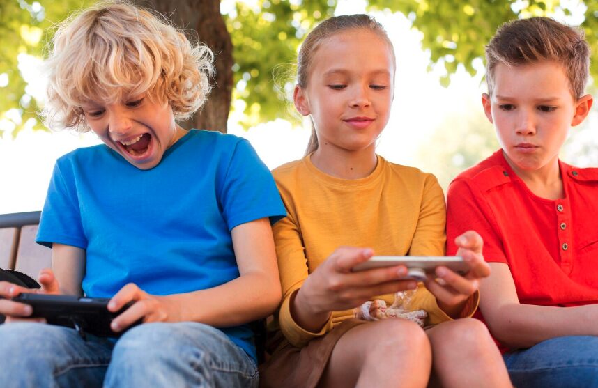Children sitting outside, looking at their smartphones
