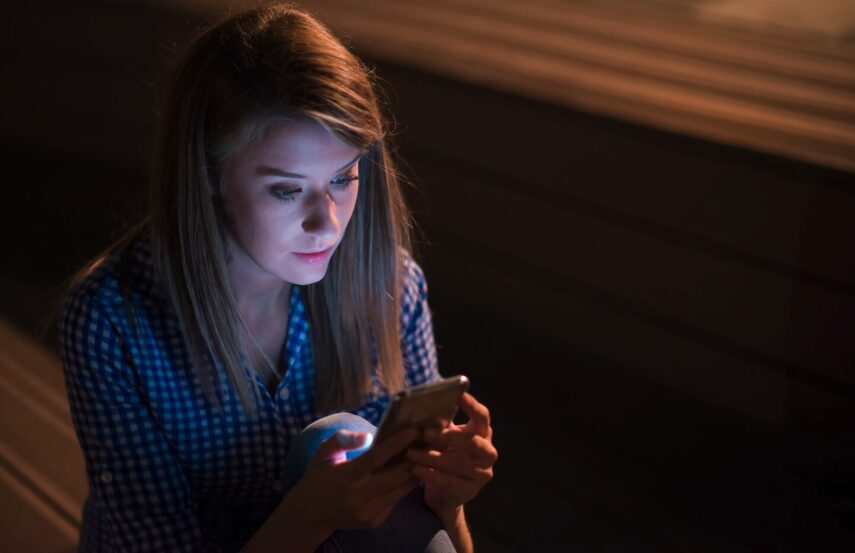 Woman in the middle of the night checking her phone for notifications