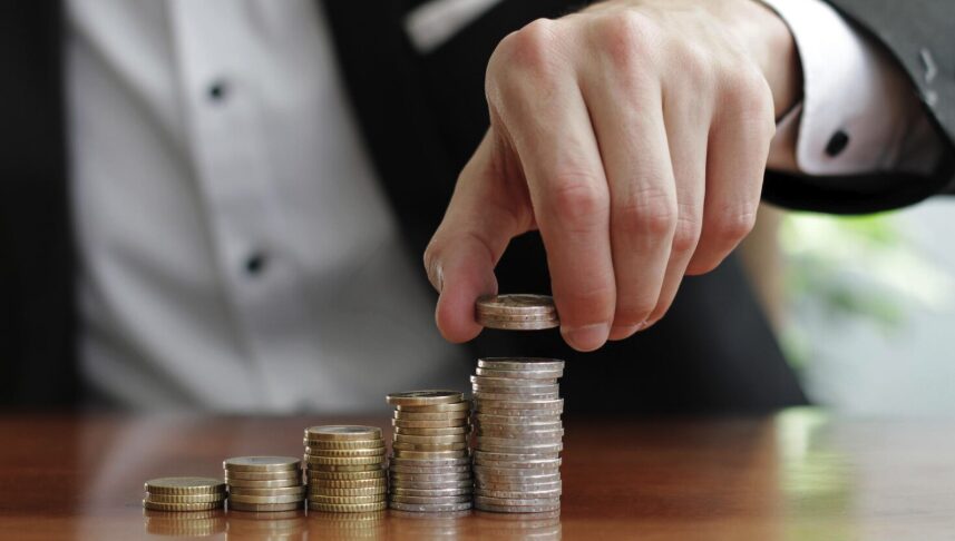 Closeup shot of a businessman's hands counting stacks of coins after business success