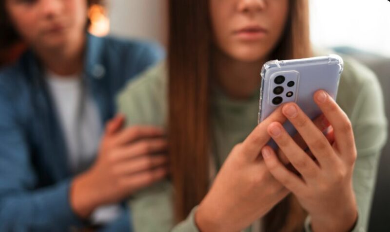 A sad girl looking at her phone being cyberbullied