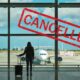 A woman with a suitcase watching a parked plane due to flight cancellations