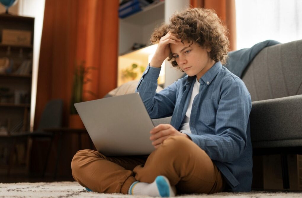 A boy sitting with his laptop and feeling sad