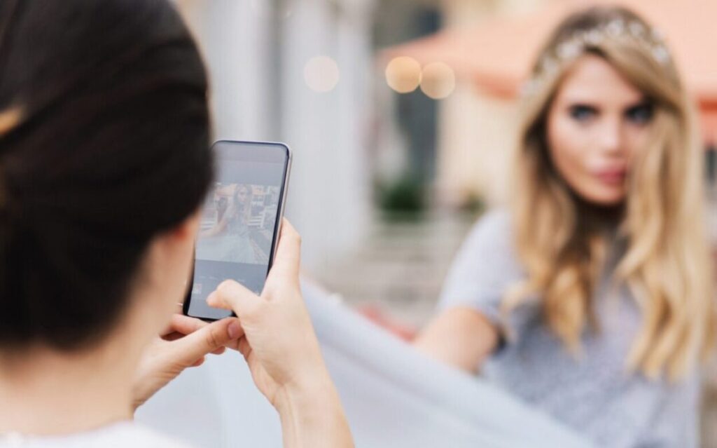 A woman taking a photo of another woman with her phone