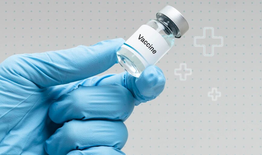 Hand in a glove holding a vaccine bottle.