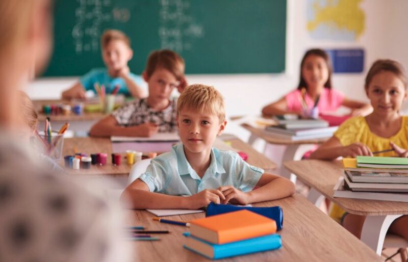A classroom with children listening to the teacher