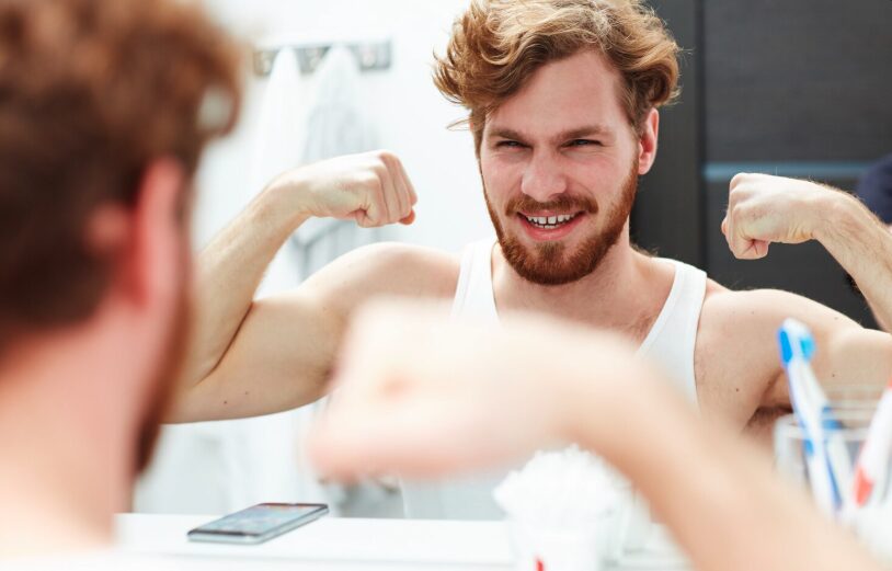 A young man checking his muscles in the mirror, suffering from bigorexia.