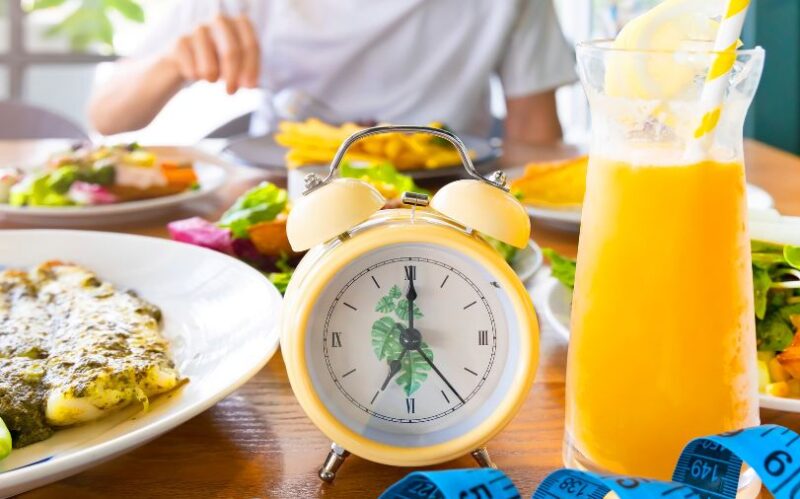 A table with clock and food prepared for ntermittent fasting