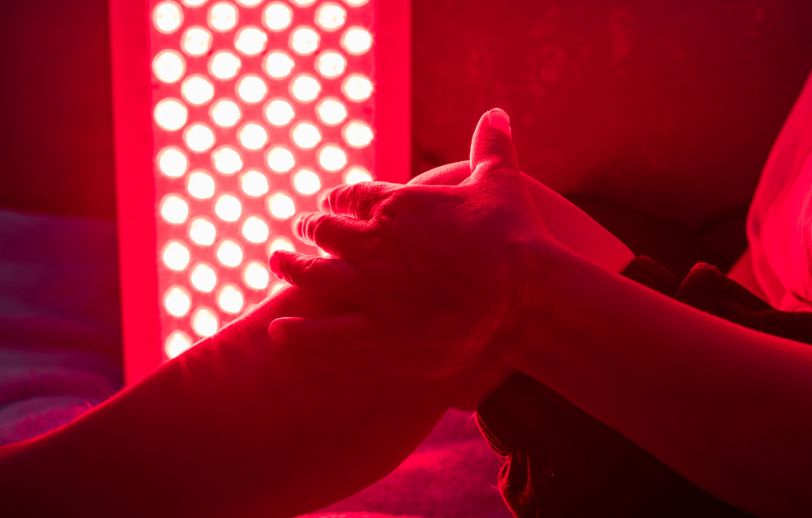 A knee in front of red light therapy panel.