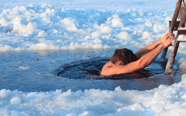 A man in an iced water doing cold plunging.