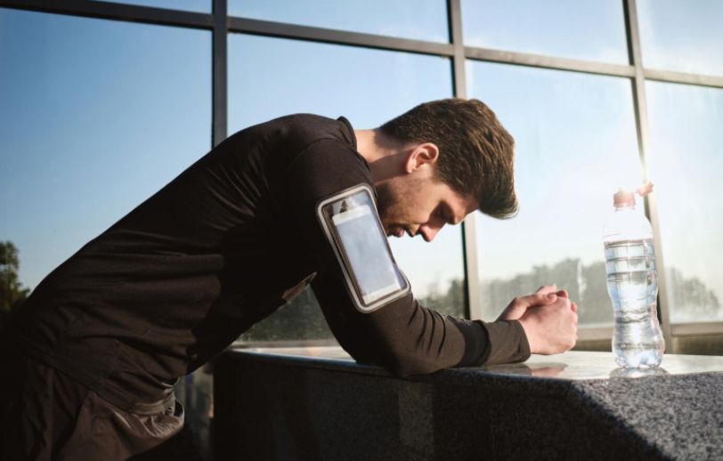A tired runner resting with smartphone tracking his workout.