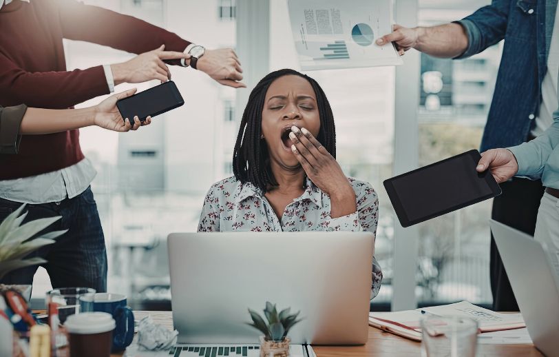 Woman yawning while getting more tasks from people.