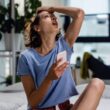 Young woman sitting on a bed feeling exhausted by optimizing her health.
