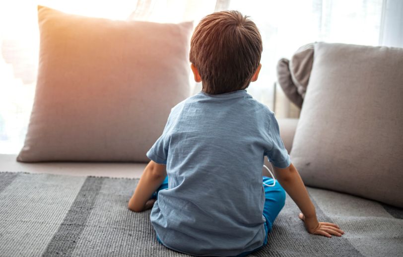 Little boy sitting on the floor with his back turned.